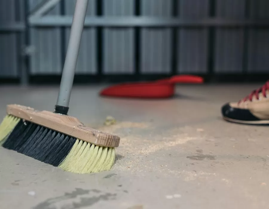 Cleaning sawdust from the floor with a broom. Cleaning up trash after work